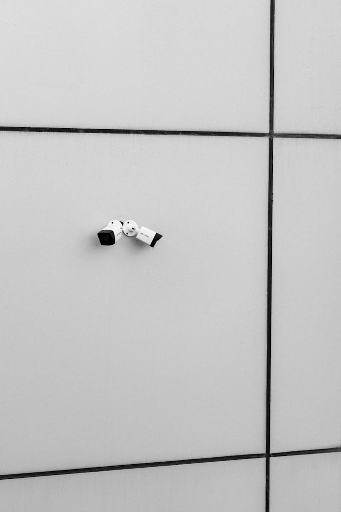 A single surveillance camera mounted on a minimalist white wall, capturing a sense of modern security.